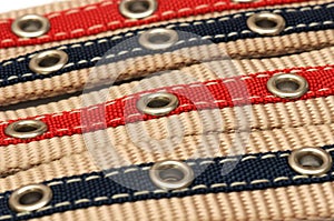 Four aligned bigger and smaler belts showing their holes notches white backdrop