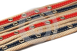 Four aligned bigger and smaler belts showing their holes notches white backdrop