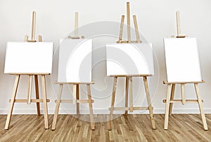 Four art studio easels with blank white painting frames