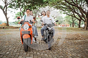 Four Asian high school students in uniform riding a motorbike