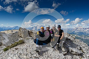 Four attractive women mountain climbers hug and smile on a mountain peak after a hard climb together