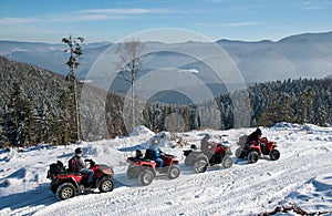 Four ATV riders on off-road quad bikes on snow in winter