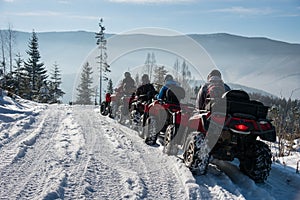 Four ATV riders on off-road quad bikes in the winter mountains