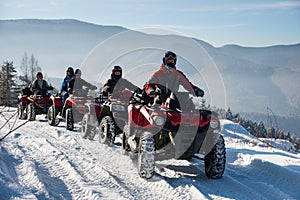 Four ATV riders on off-road four-wheelers ATV bikes in the winter mountains