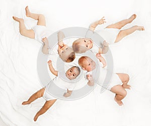 Four babies lay in star shape on white background