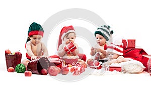 Four babies in xmas costumes playing among gifts