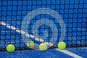 Four balls in a blue paddle tennis court, racquet sports concept