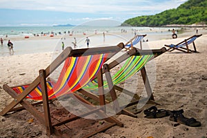 Four beach armchair with leather slippers with tourists on sandy beach