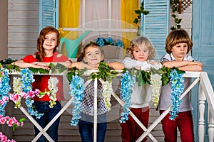 Four beautiful children, two boys and two girls stand on a wooden threshold and laugh