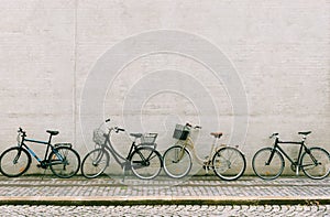 Four bicycles stand near a white brick wall