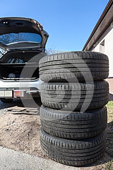 Four big wheels with summer tire are ready for loading inside the trunk of a passenger car