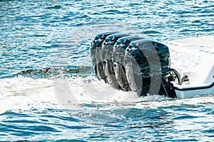 Four, black, 400 horsepower, outboard motors, moving a power boat