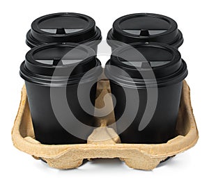 Four black takeaway cups of coffee in a tray on white background