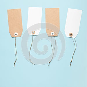 Four blank paper price tag with a knotted string on a blue