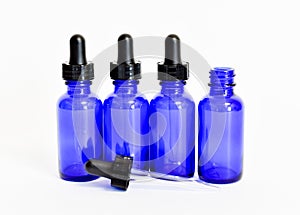 Four blue glass eyedropper bottles, one removed photo