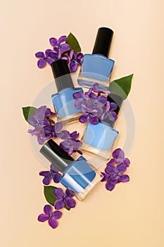 Four blue nail polish bottles on orange background. Set of blue nail polish bottles with purple lilac decoration