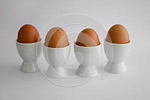 Four boiled eggs in egg cups, on white background photo