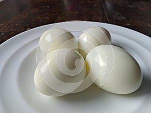 four boiled eggs served on white plate
