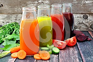 Four bottles of healthy vegetable juice with a rustic wood background