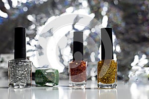 The Four bottles of nail polish on a white background The back is a silver bokeh, blurred in circles
