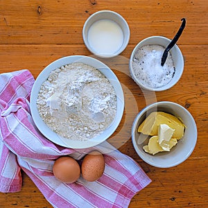 Ingredients for biscuits cookies in bowls on a wooden table with red and white striped kitchen towel photo