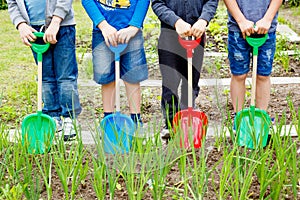 Four boys playing with plastic shovels in the garden