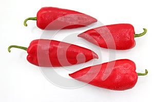 Four bright red sweet peppers on a white background