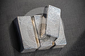 Four bullion bars of precious metal on a gray background.