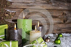 Four burning apple green christmas candles on wooden background.