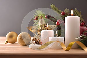 Four burning candles on wooden table with Christmas decoration front