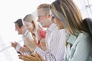 Four business people applauding indoors smiling