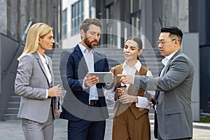 Four business people discussing financial results of achievement, mature men and women outside office building