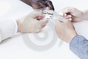 Four business people holding jigsaw puzzle pieces and placing them together, hands only