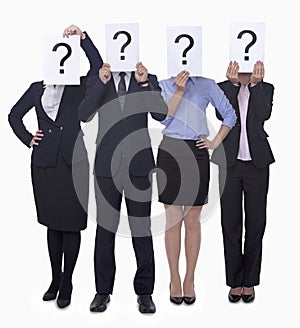 Four business people holding up paper with question mark, obscured face, studio shot photo