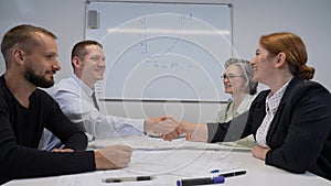 Four business people make a deal and shake hands. Slow motion.