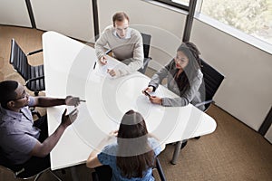 Four business people sitting at a conference table and discussing during a business meeting