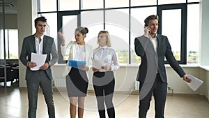 Four business people talking and walking in office lobby