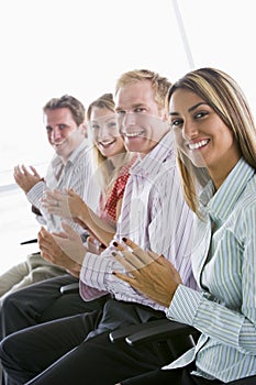 Four businesspeople applauding indoors smiling