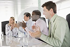 Four businesspeople in a boardroom applauding