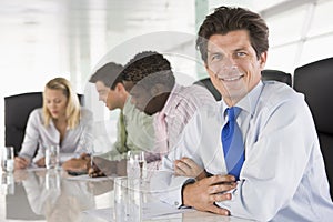 Four businesspeople in a boardroom smiling