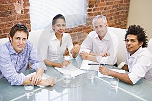 Four businesspeople in boardroom smiling