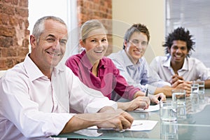 Four businesspeople in boardroom smiling