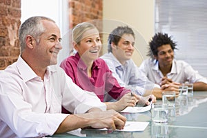 Four businesspeople in boardroom smiling