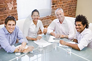 Four businesspeople in boardroom smiling