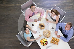 Four businesspeople eating at boardroom table