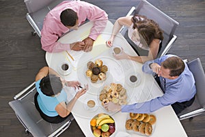 Four businesspeople eating at boardroom table