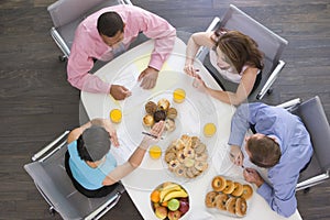 Four businesspeople eating at boardroom table