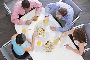 Four businesspeople eating at boardroom table