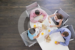 Four businesspeople eating at boardroom table