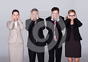 Four businesspeople holding their ears